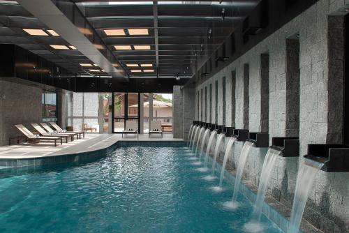 a pool with chairs and waterfalls in a building at Exclusive Gramado Hotel & Spa by Gramado Parks in Gramado