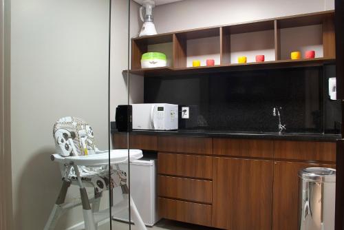 a kitchen with a counter with a microwave and a stool at Exclusive Gramado Hotel & Spa by Gramado Parks in Gramado