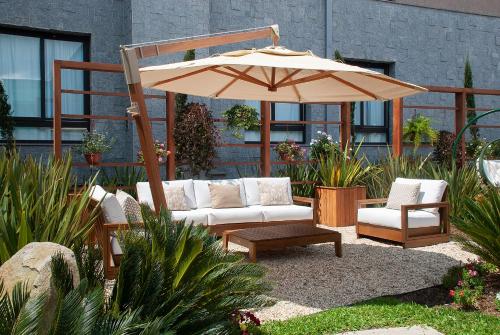 a patio with a couch and an umbrella at Exclusive Gramado Hotel & Spa by Gramado Parks in Gramado
