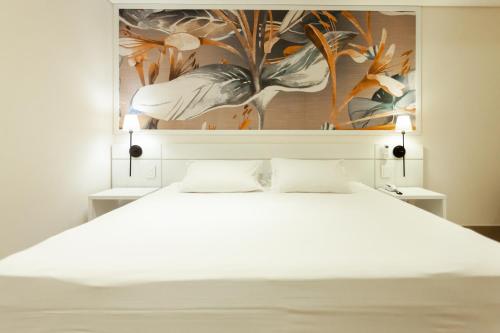 a bedroom with a white bed with a painting on the wall at Vistabela Resort & Spa in São Sebastião