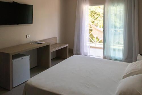 a bedroom with a bed and a television and a window at Vistabela Resort & Spa in São Sebastião