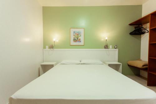 a white bed in a bedroom with green walls at Vistabela Resort & Spa in São Sebastião
