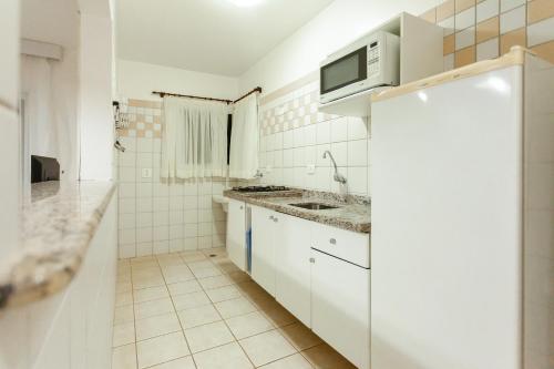 a white kitchen with a sink and a microwave at Vistabela Resort & Spa in São Sebastião