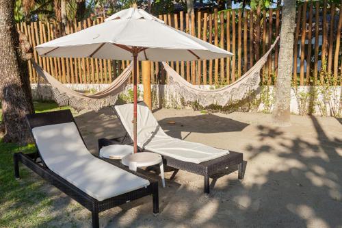 a patio with two chairs and an umbrella at Vistabela Resort & Spa in São Sebastião