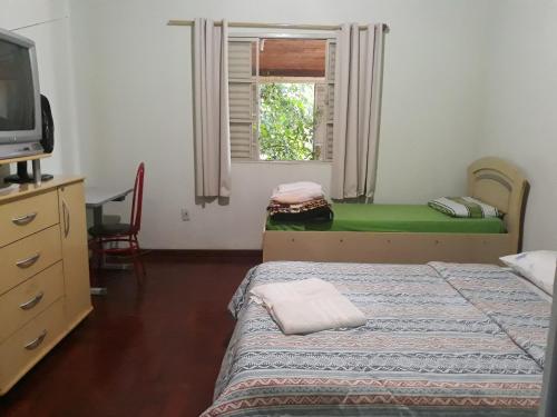a bedroom with two beds and a tv and a window at Pousada do Ribeirão in Andrelândia