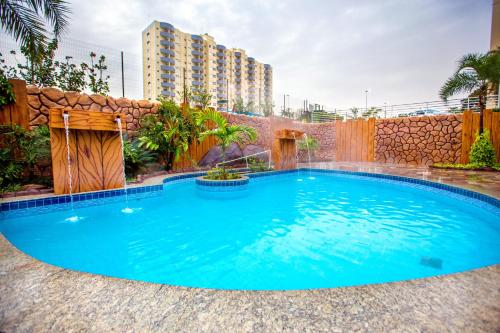 a large blue pool with a waterfall in a backyard at Golden Dolphin Grand Hotel via Giro ImobTech in Caldas Novas