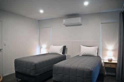 two beds in a small room with two lamps at Whakatane B&B in Whakatane