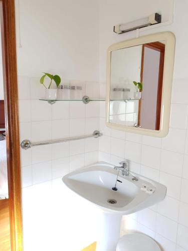 a white bathroom with a sink and a mirror at Pensão David, B&B in São Pedro do Sul