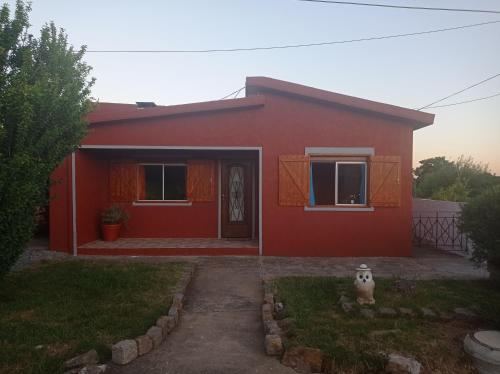 uma casa vermelha com uma porta da frente e um quintal em Hosteling Las Margaritas em Minas