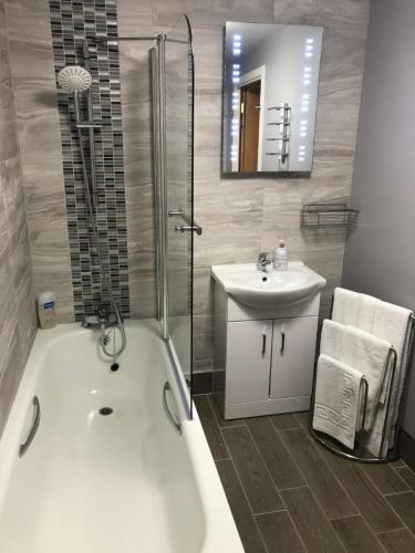 ein Badezimmer mit einer weißen Badewanne und einem Waschbecken in der Unterkunft GRAPHITE APARTMENTS in Inverness