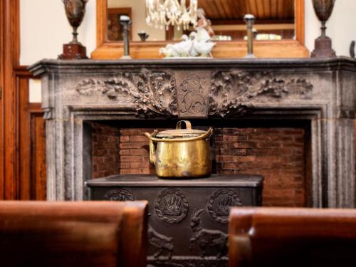 een gouden pot bovenop een open haard bij Beautiful castle house in Spa authenticly decorated and with spacious garden in Spa
