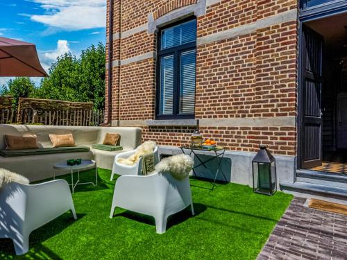 a patio with a couch and chairs on grass at Luxurious holiday home in Heers with terrace in Mettekoven