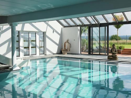 ティユーにあるHoliday home in Theux with indoor swimming pool and wellnessのガラスドア付きの家のスイミングプール、スイミングプール