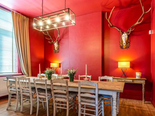 une salle à manger avec une table en bois et des murs rouges dans l'établissement Luxurious holiday home in Heers with terrace, à Mettekoven