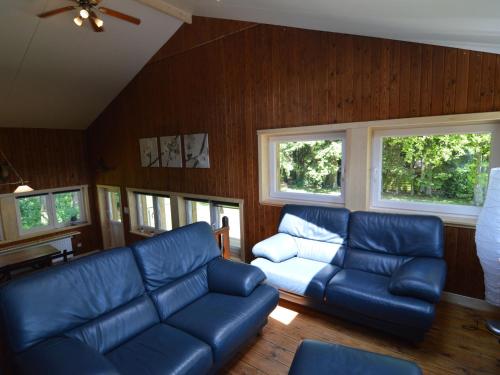 uma sala de estar com mobiliário de couro azul e janelas em Welcoming Cottage in Hatrival with Terrace em Saint-Hubert