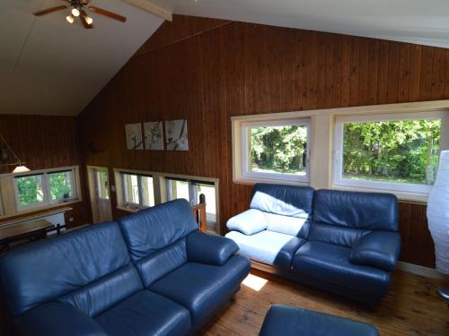 a living room with blue leather furniture and windows at Welcoming Cottage in Hatrival with Terrace in Saint-Hubert