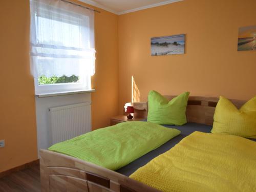 1 dormitorio con 2 camas con almohadas verdes y ventana en Beachside Bungalow, Boiensdorf, en Boiensdorf