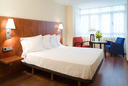 una habitación de hotel con una cama grande y sillas en Hotel Arena, en Gijón