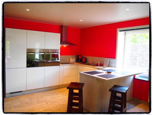 a kitchen with red walls and a counter with stools at Comfy holiday home with terrace in Ellezelles in Ellezelles
