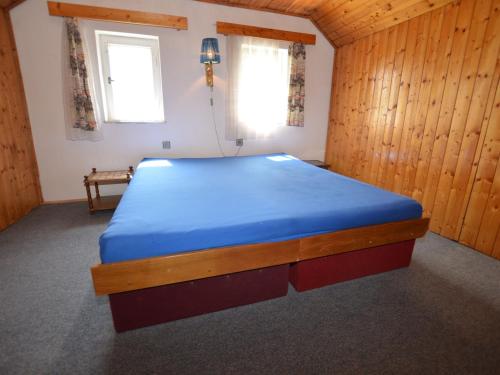 a bedroom with a blue bed in a wooden room at Detached cottage with fireplace, only 80 meters from the river Ohre in Radonice nad Ohří