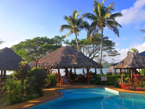 um resort com piscina e palmeiras em Poppy's on the Lagoon em Port Vila