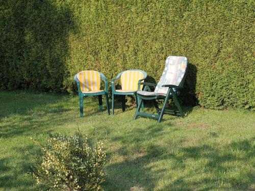 three chairs sitting in the grass next to a hedge at Wohnung mit großem Garten an der Ostseeküste in Neubukow