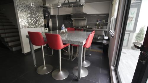 a kitchen with a black counter with red chairs at 2 Bedroom Garden House Polanco in Mexico City