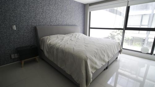 a bedroom with a bed with a white comforter and a window at 2 Bedroom Garden House Polanco in Mexico City