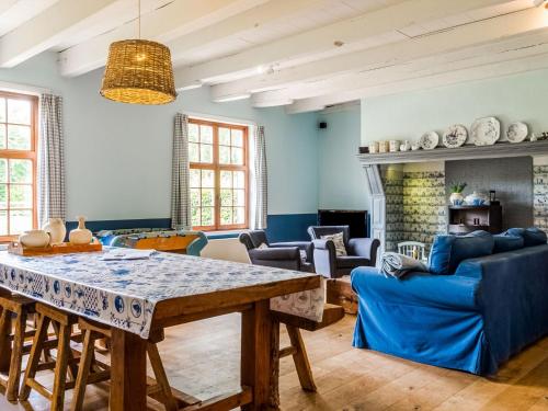 a living room with a table and blue furniture at Historic Farmhouse in the middle of polder landscape Damme in Oedelem