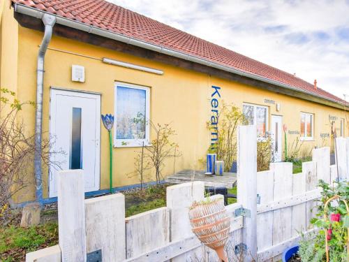 a yellow house with a white fence in front of it at Wohnung nahe Ostsee Graal Müritz Strand in Rövershagen