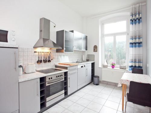 a kitchen with white cabinets and a stove top oven at Moderne Villa in Borstendorf mit Park in Leubsdorf
