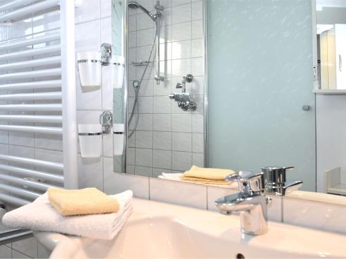 a bathroom with a sink and a shower with a mirror at Attractive apartment in Bellenberg with garden in Horn-Bad Meinberg