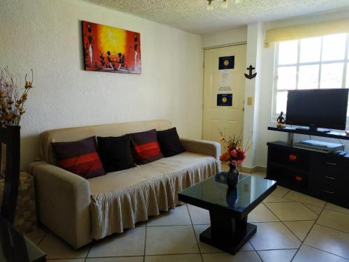 a living room with a couch and a tv at Departamento Las Gaviotas in Acapulco
