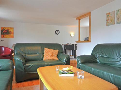 a living room with two green leather couches and a table at Holiday home in Sauerland with garden in Schmallenberg