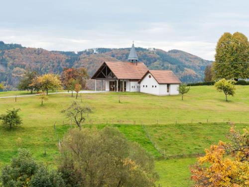 a white house in a field with a church at Apartment on the edge of the forest in Kleines Wiesental