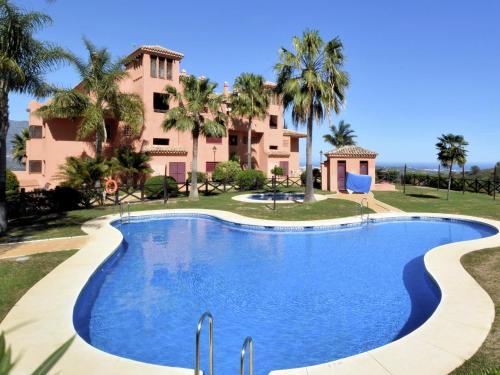 a swimming pool in front of a house with palm trees at Belvilla by OYO El Soto de Marbella in Ojén