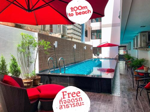 a swimming pool with red umbrellas and tables and chairs at Scandia Beach Hotel - Soi 7 Best Location - 200m to Beach next to Food Market in Jomtien Beach