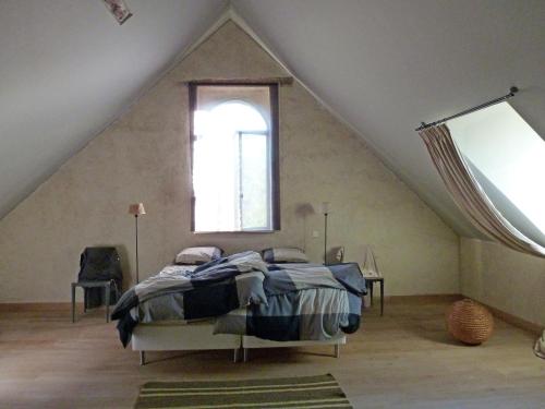 a bedroom with a bed in a attic with a window at Beautiful farmhouse in Braize with private garden in Coust