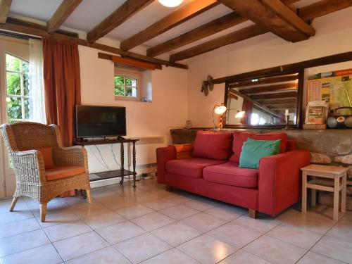 a living room with a red couch and a tv at Holiday Home in Saizy with Patio in Vignol