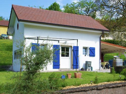 una pequeña casa blanca con puertas azules y un patio en Cosy holiday home with garden en Fresse-sur-Moselle