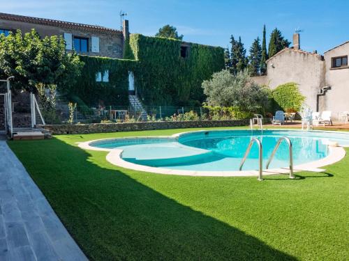 a swimming pool in a yard next to a house at Stone cottage on an active wine growing estate with a swimming pool in Conilhac-Corbières