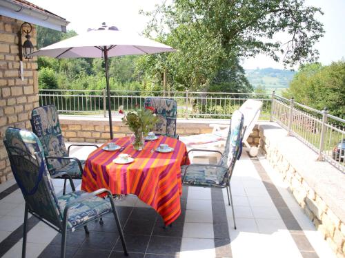 una mesa y sillas en un patio con sombrilla en Authentic holiday home in the Champagne region, en Laferté-sur-Amance