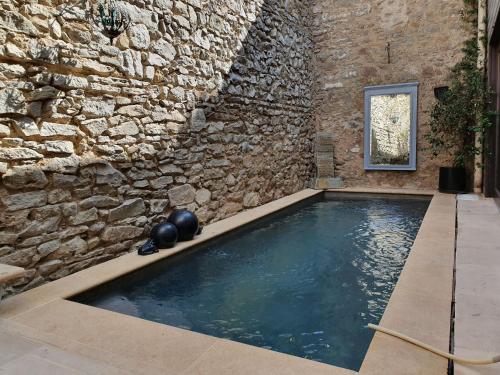 a swimming pool in front of a stone wall at Holiday home near the Canal du Midi in Olonzac