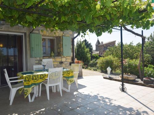 een eettafel en stoelen op een patio met een boom bij Peaceful holiday home with pool in Saint-Pons