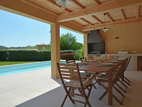 patio con mesa de madera, sillas y piscina en Luxury villa with private swimming pool, en Malaucène