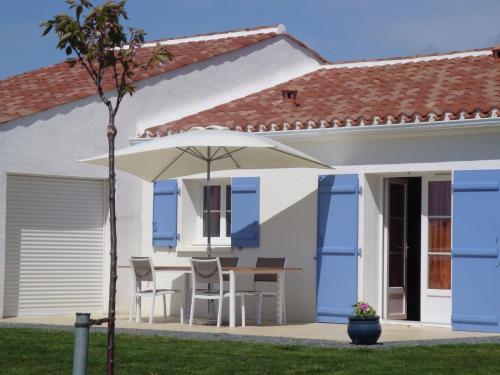 une maison blanche avec une table, des chaises et un parasol dans l'établissement Modern holiday home with a garden near the beach, à Saint-Hilaire-la-Forêt