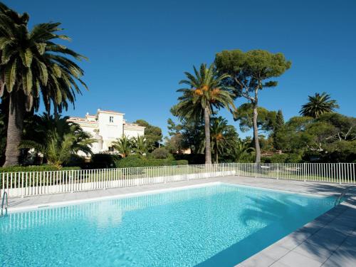 a swimming pool with a fence and palm trees at Apartment in villa with pool and beach access in Saint-Raphaël