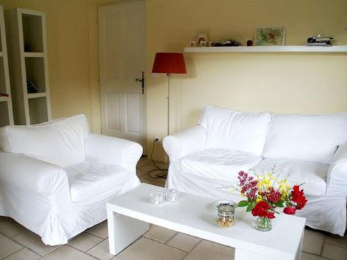 - un salon avec deux canapés blancs et une table fleurie dans l'établissement Cycling Escape in Montbrun, à Montbrun-les-Bains