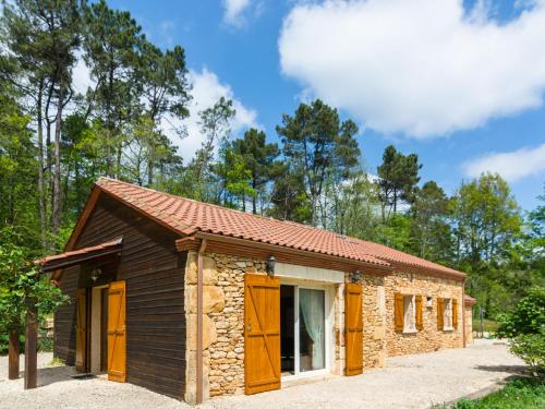 een klein stenen huis met oranje deuren in een bos bij Picturesque holiday home with pool in Saint-Cernin-de-lʼHerm