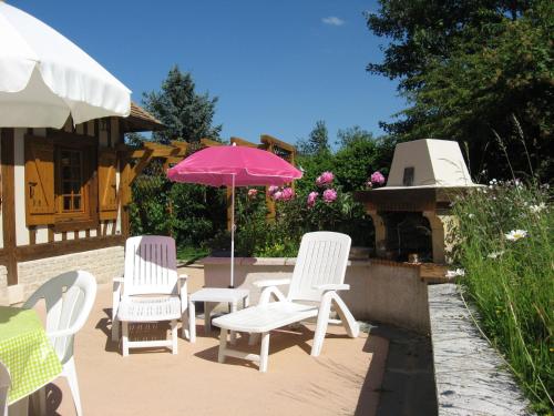 a group of chairs and an umbrella on a patio at Traditional house with garden in Dampsmesnil in Écos